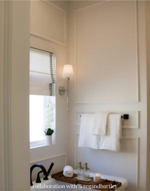 Classic Tall Three Piece Wall Moulding Kit installed as an accent wall in a bathroom with 10' ceilings. Three-panel layout with middle rail detail.Bathroom interior with towels on a rack, window, and light fixture.